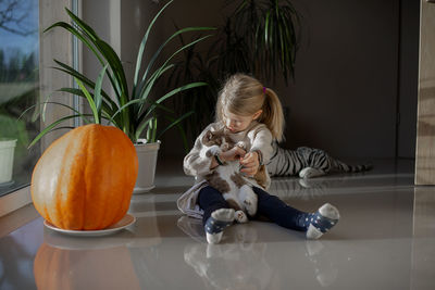 Cute girl playing with cat playing at home