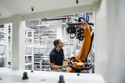 Technician examining industrial robot in a factory