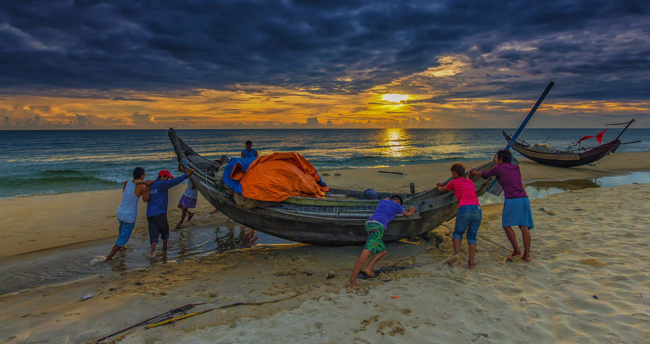 MEN FISHING ON BEACH AGAINST SKY