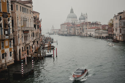 Boats in canal amidst buildings in city