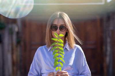 Young woman wearing sunglasses while holding twig