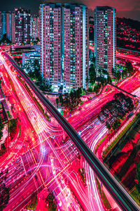 High angle view of light trails on city street by buildings