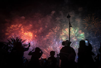 Silhouette people with fire crackers at night