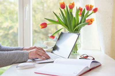 Midsection of woman using laptop at home