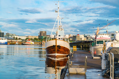 Sailboats moored at harbor in city against sky