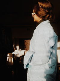 Side view of woman standing in darkroom