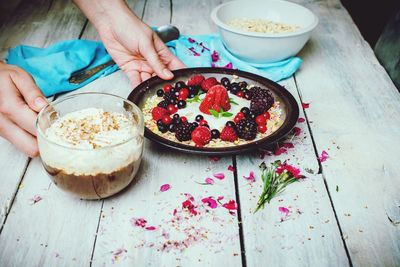 Midsection of woman holding ice cream and spoon on table