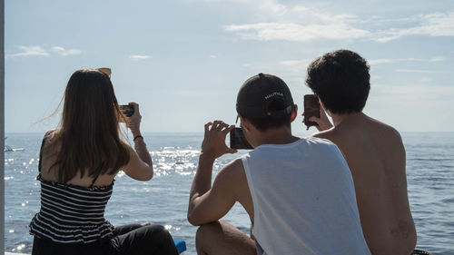 Rear view of people on beach against sky