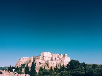 Men and women on cliff against acropolis old ruins