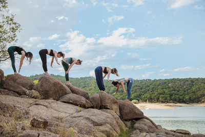 People standing on rock by sea against sky