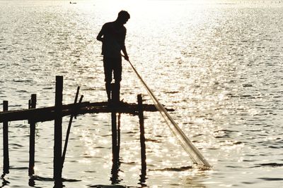 Silhouette man standing in sea against sky