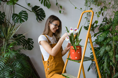 Young woman smiling while standing by flowering plants at store