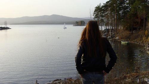 Rear view of woman standing at shore of lake turgoyak