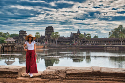 Woman standing at riverbank against sky