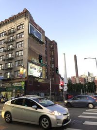 Cars on road by buildings against clear sky
