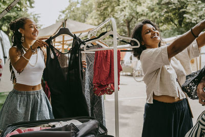 Smiling women buying dress at flea market
