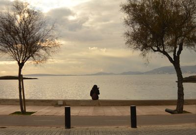 Rear view of silhouette woman looking at sea against sky
