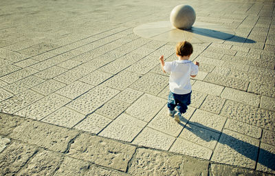 Full length rear view of child running towards stone ball