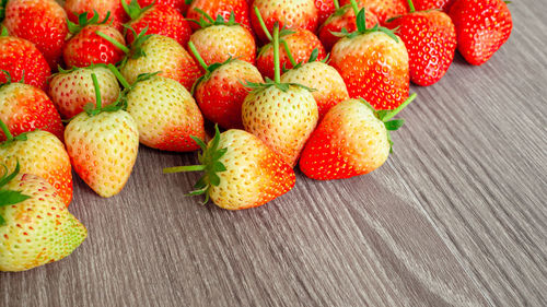 Top view photo, a heap of fresh berry fruit, red strawberry on wooden background with coppy space