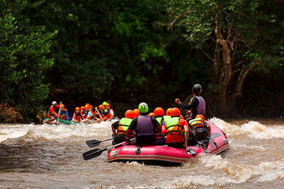 People in boat on river against trees