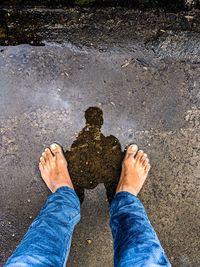 Low section of man standing by water on land