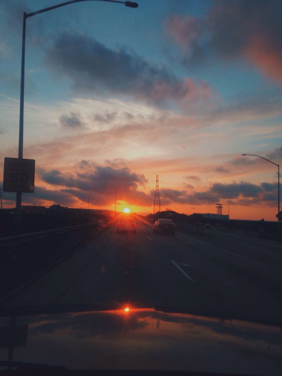 sunset, transportation, car, road, sky, land vehicle, mode of transport, sun, cloud - sky, silhouette, orange color, street, street light, road marking, sunlight, the way forward, cloud, nature, no people, windshield