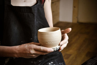 A raw clay pot in the hands of a potter. master crock.