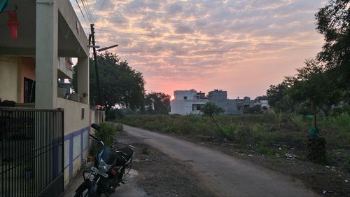 Road amidst trees against sky during sunset