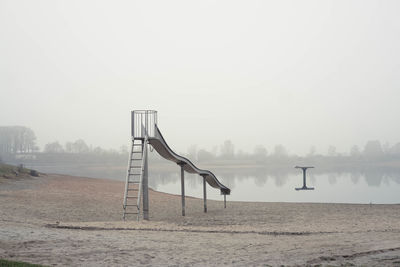 Lifeguard hut in winter against sky during foggy weather