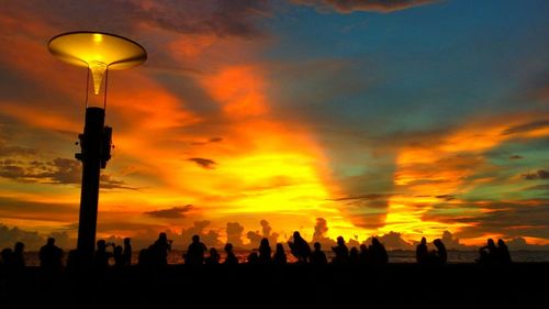Silhouette people against dramatic sky during sunset