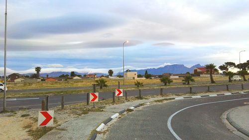 Road passing through landscape against cloudy sky