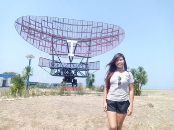 Full length of young woman standing against clear sky