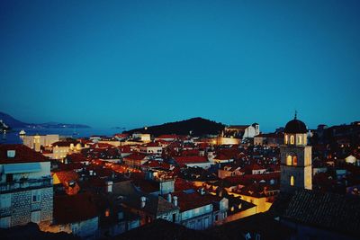 High angle view of illuminated cityscape against clear blue sky