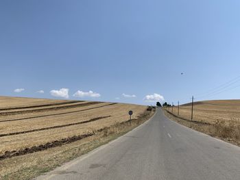 Road amidst field against sky