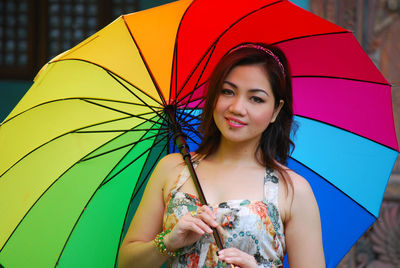 Portrait of woman with colorful umbrella standing in rain