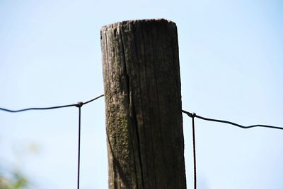 Low angle view of wooden post against sky