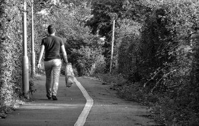 Rear view of man walking on road