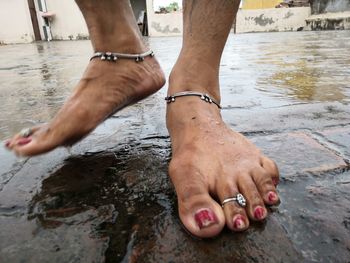 Low section of woman standing on wet footpath