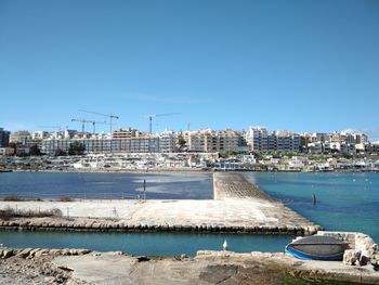 City at waterfront against blue sky