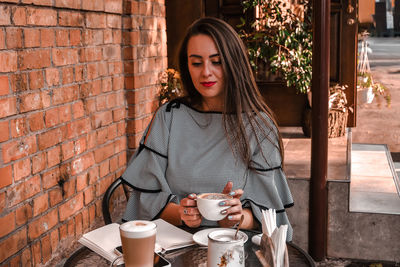 Woman holding coffee cup against wall