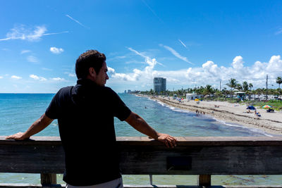 Man standing by railing against sea