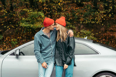 A young couple in love is embracing near the car.