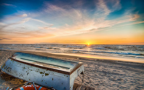 Close-up of beach against dramatic sky during sunset