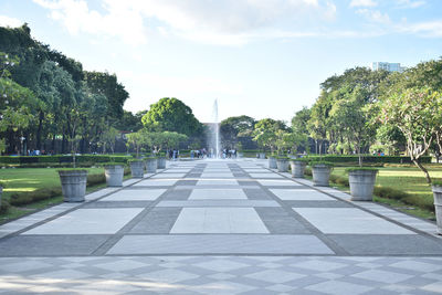 View of footpath in park against cloudy sky