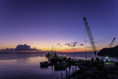 Sailboats moored on sea against sky during sunset