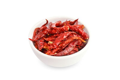 Close-up of red chili peppers in bowl against white background