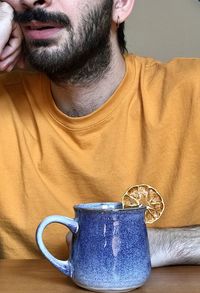 Midsection of man sitting by cup on table