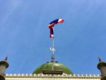 Low angle view of flags on building against blue sky