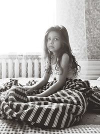 Portrait of smiling girl sitting on bed at home