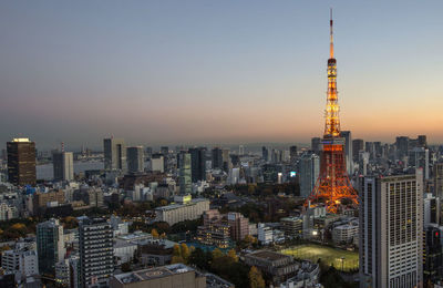 Illuminated tokyo tower in city against clear sky during sunset